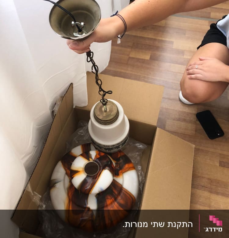 מנורה עם חוטי חשמל חשופים ביד אדם